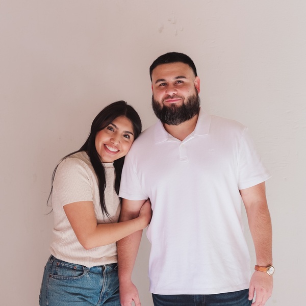 Mariah Hipolito and her husband smiling together in a studio portrait