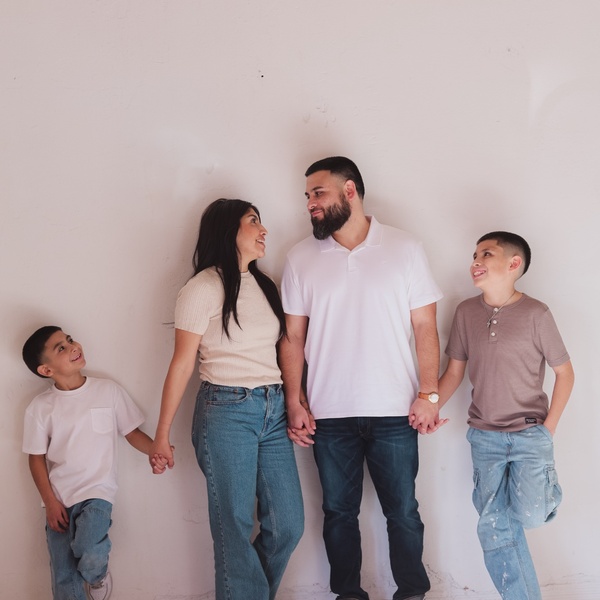 Mariah Hipolito standing with her husband and two sons, holding hands and smiling